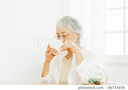 Elderly woman drinking a drink in a mug 86754856