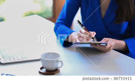 Cropped shot businesswoman holding pen and writing information on notebook. Cropped shot businesswoman holding pen and writing information on notebook. 86755415