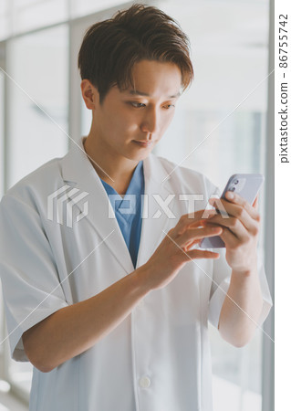 A man in a white coat and a smartphone A man in a white coat and a smartphone 86755742