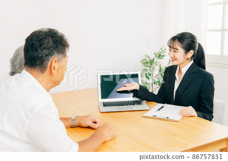 A woman in a suit and an elderly couple explaining on a computer 86757831