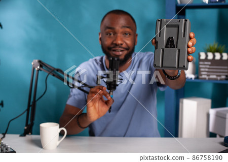 Selective focus on social media influencer hand holding v mount rechargeable battery 86758190