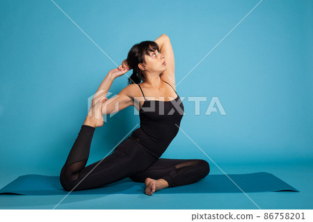 Athletic woman sitting on yoga mat stretching leg during fitness workout 86758201