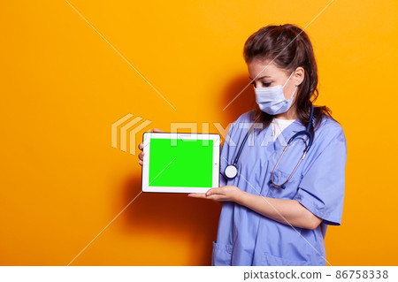 Nurse looking at horizontal green screen on digital tablet 86758338