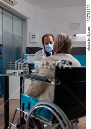 Doctor meeting with retired person sitting in wheelchair at checkup visit Doctor meeting with retired person sitting in wheelchair at checkup visit 86758393