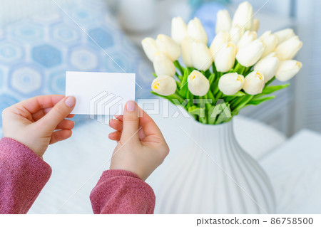 Woman pulling blank greeting card from bouquet of white tulips flowers. Mother day, Copy space. Mock up Woman pulling blank greeting card from bouquet of white tulips flowers. Mother day, Copy space. Mock up 86758500