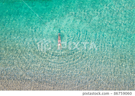 Top, aerial view. Young beautiful woman in a hat and white bikini swimming in sea water on the sand beach. Drone, copter photo. Summer vacation. View from above. Top, aerial view. Young beautiful woman in a hat and white bikini swimming in sea water on the sand beach. Drone, copter photo. Summer vacation. View from above. 86759060
