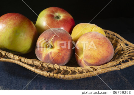 Peaches and apples in a basket on the table Peaches and apples in a basket on the table 86759298