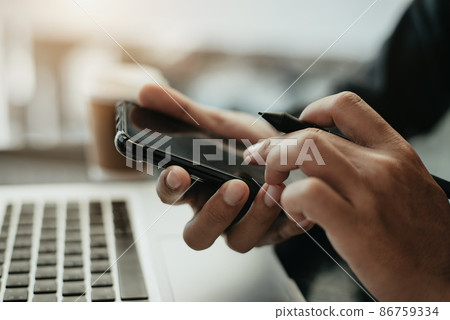 Close up hands multitasking man using smartphone and laptop connecting wif. 86759334