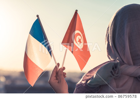 Muslim woman in scarf with Tunisia and French flags of at sunset.Concept Muslim woman in scarf with Tunisia and French flags of at sunset.Concept 86759578