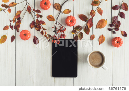 tablet and cup of coffee with leaves, small pumpkins and rowan on white retro wood boards. background. Autumn, fall concept. Flat lay, top view. Instagram style 86761376