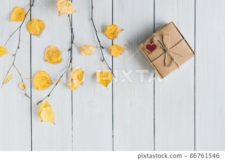 Woman packing gift in a box of kraft paper on white retro wood boards. leaves, birch branches. Thanksgiving. Autumn, fall concept. Flat lay, top view. 86761546