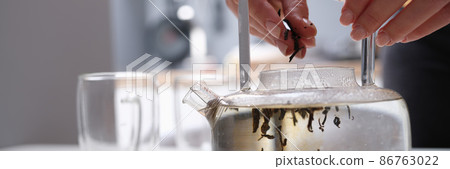 Woman falls asleep tea leaves in transparent glass teapot with hot water Woman falls asleep tea leaves in transparent glass teapot with hot water 86763022