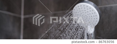 Running water pours from chrome-plated shower mixer closeup 86763056