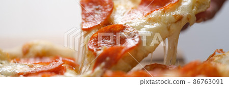 Slice of juicy fresh hot pizza is taken out of box closeup Slice of juicy fresh hot pizza is taken out of box closeup 86763091