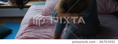 Lonely sad woman sits on bed closeup 86763092