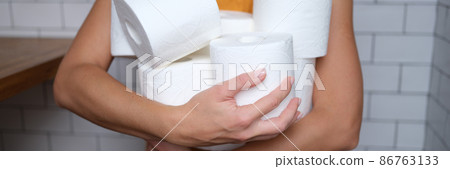 Woman holding many rolls of toilet paper in bathroom closeup Woman holding many rolls of toilet paper in bathroom closeup 86763133