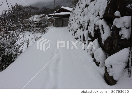 雪覆蓋的石牆、道路、田野、樹木、私人住宅和山脈的鄉村冬季晨景 86763630