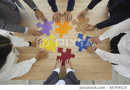 Top view of employees or workers brainstorm connect jigsaw puzzles involved in teambuilding activity in office. Diverse businesspeople team join pieces solve business solution. Teamwork concept. 86764029