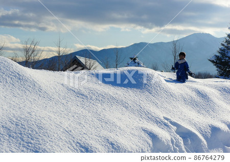 A boy playing in a snowy mountain under the blue sky A boy playing in a snowy mountain under the blue sky 86764279