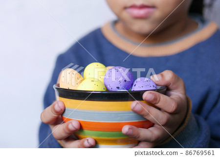 child hand holding a bowl of easter eggs on pink child hand holding a bowl of easter eggs on pink 86769561