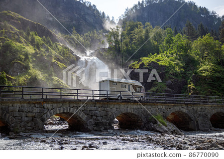 Holiday trip in motorhome, Caravan car Vacation. RV traveling on the road Latefossen Waterfall Odda Norway. Latefoss is a powerful, twin waterfall. Holiday trip in motorhome, Caravan car Vacation. RV traveling on the road Latefossen Waterfall Odda Norway. Latefoss is a powerful, twin waterfall. 86770090