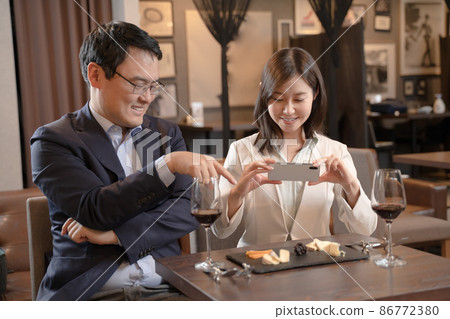 男人和女人在餐廳用智能手機拍攝食物照片 86772380