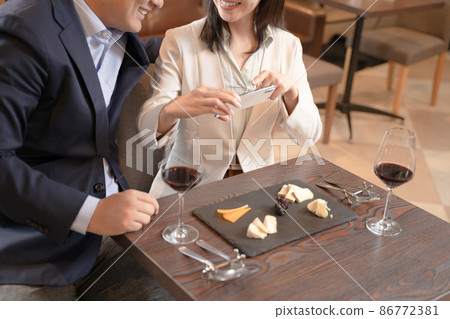 男人和女人在餐廳用智能手機拍攝食物照片 86772381