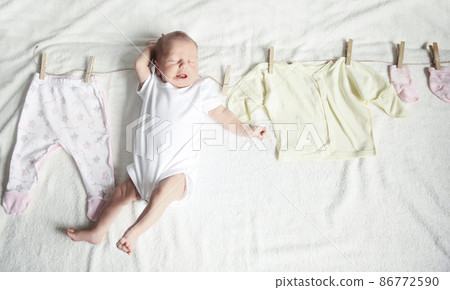 baby clothes on the clothespin and the newborn baby 86772590