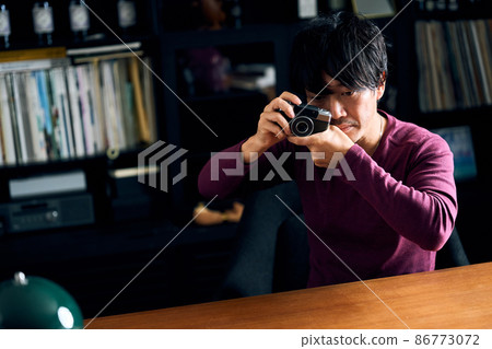 A man playing with his hobby camera in his study 86773072