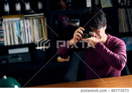 A man playing with his hobby camera in his study 86773073