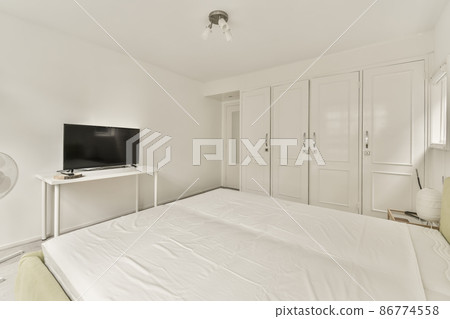 Large double bed in the center of the room with a white duvet cover in a small room 86774558