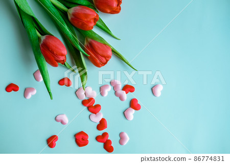 bouquet of red tulips with small hearts on a blue background, top view bouquet of red tulips with small hearts on a blue background, top view 86774831