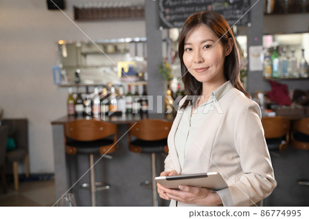 A woman who runs a restaurant with a tablet A woman who runs a restaurant with a tablet 86774995