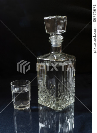 Vodka in a decanter and a glass on the table with a reflection 86775671