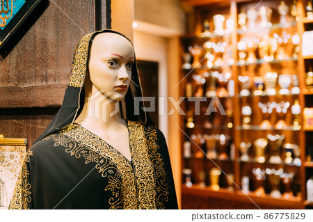 Mannequins dressed in beautiful female woman traditional arabian dresses, clothes in store or outdoor market. Oriental dress in shopping center. Popular souvenirs from Dubay, UAE, United Arab Emirates 86775829