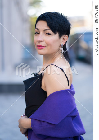 An elegant woman in a stylish outfit poses on a city street An elegant woman in a stylish outfit poses on a city street 86776599