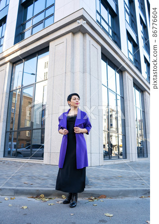 An elegant woman in a stylish outfit poses on a city street An elegant woman in a stylish outfit poses on a city street 86776604