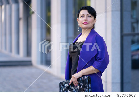 An elegant woman in a stylish outfit poses on a city street An elegant woman in a stylish outfit poses on a city street 86776608