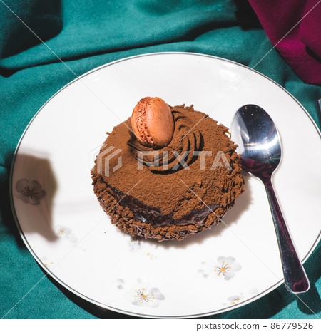 Chocolate cake covered with cocoa powder and decorated with macarons, caramel waffles, truffles and cookie sticks 86779526