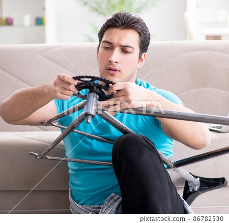 Young man repairing bicycle at home Young man repairing bicycle at home 86782530