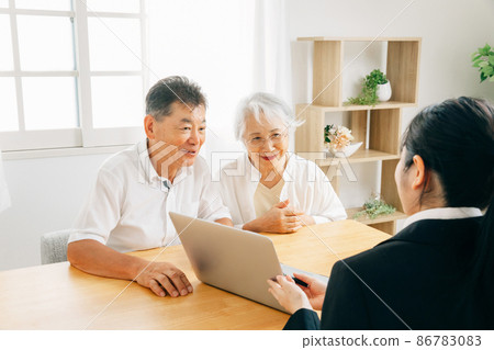 A woman in a suit and an elderly couple explaining on a computer A woman in a suit and an elderly couple explaining on a computer 86783083