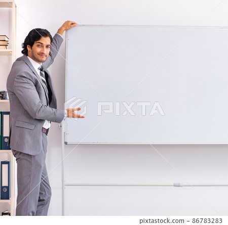 The young handsome businessman standing in front of whiteboard The young handsome businessman standing in front of whiteboard 86783283