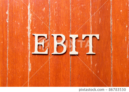 Alphabet letter in word EBIT (Abbreviation of Earnings Before Interest and Taxes) on old red color wood plate background 86783530