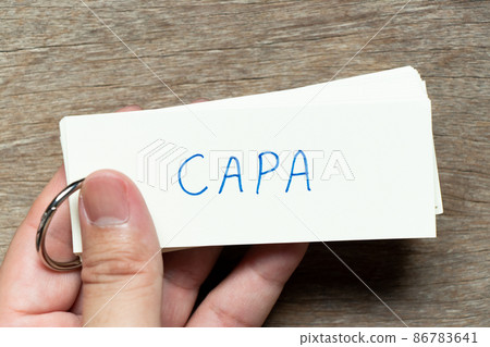 Man hold the flash card with handwriting word CAPA (abbreviation of corrective action and preventive action) on wood background 86783641