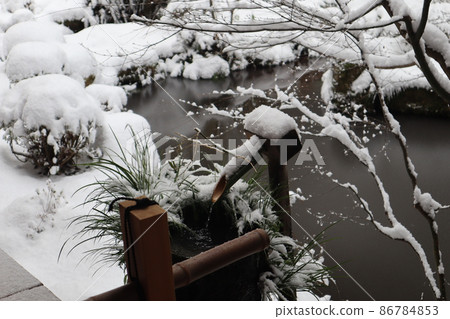 A landscape with a bamboo tsukubai and a stone chozubachi in a frozen pond and a snow-covered garden A landscape with a bamboo tsukubai and a stone chozubachi in a frozen pond and a snow-covered garden 86784853