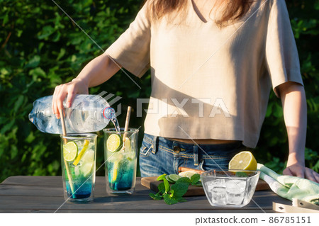 Girl makes summer refreshing cocktails blue lagoon. Process of pouring water into glasses. Selective focus Girl makes summer refreshing cocktails blue lagoon. Process of pouring water into glasses. Selective focus 86785151
