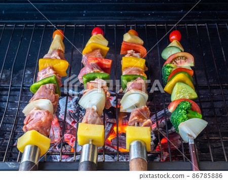Grilled barbecue sticks on fire, beef, pork, chilli, peppers, pineapple, onion and tomato, for outdoor dining Grilled barbecue sticks on fire, beef, pork, chilli, peppers, pineapple, onion and tomato, for outdoor dining 86785886