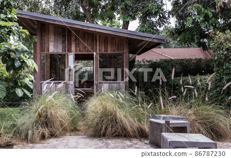 Nice small wooden hut. Green garden joy in summer with Stone benchs and perennial ryegrass plant. Nice small wooden hut. Green garden joy in summer with Stone benchs and perennial ryegrass plant. 86787230