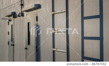 White metal fire escape attached and Two doors to a wall and leading to the roof of a building. 86787442