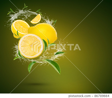 Water splash on fresh lemon and tea leaves isolated on green background. Water splash on fresh lemon and tea leaves isolated on green background. 86789664